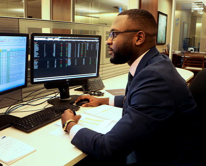 man at a computer workstation displaying financial information